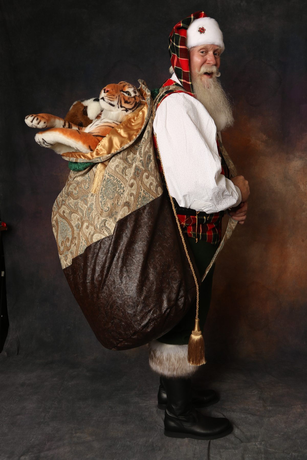 Santa Pat carrying a large ornate toy sack with a stuffed tiger peeking out