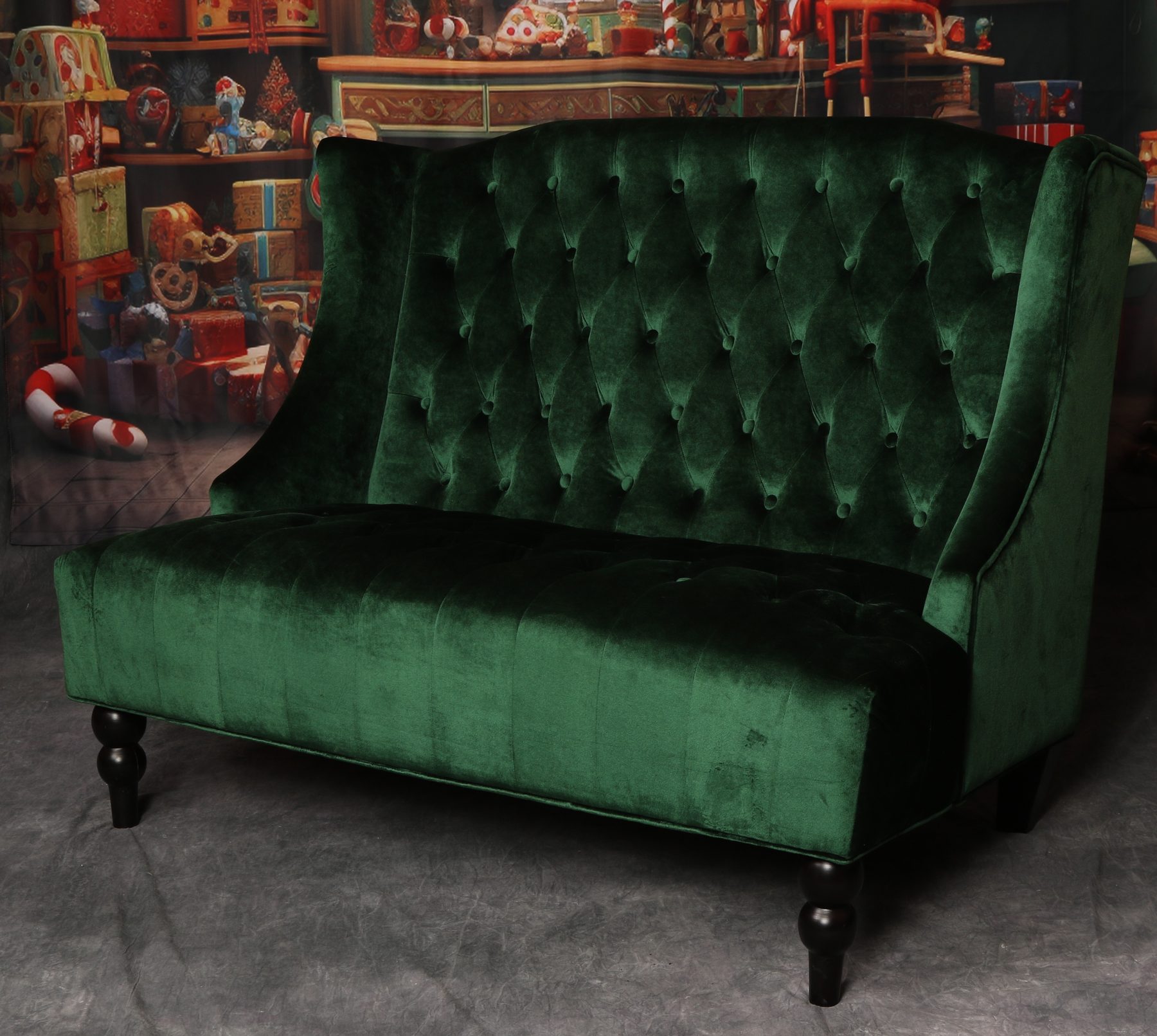 The green velvet tufted loveseat available to rent for Santa Pat's visits